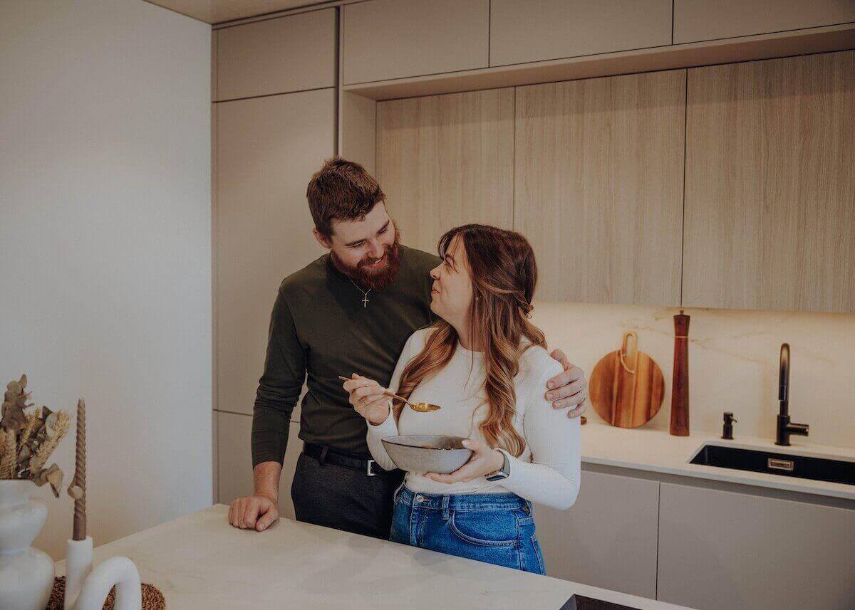 Paar genießt ayurvedisches Gericht mit Gewürzreis in moderner Küche.